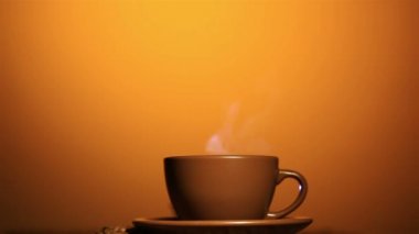 Sıcak bir içecek ve kahve taneleri, buhar, turuncu arka plan ile kahverengi Kupası.