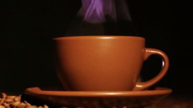 Sıcak bir içecek ve kahve taneleri, buhar, kahverengi Kupası kapatın. Merkezinde