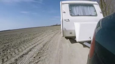 Yeşil araba ile karavan römork gitmek ve toprak yolda durdurmak.