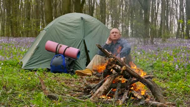 Slow motion naar 100 Fps. volwassene man in de buurt van kampvuur en tent met rugzak hebben rest — Stockvideo