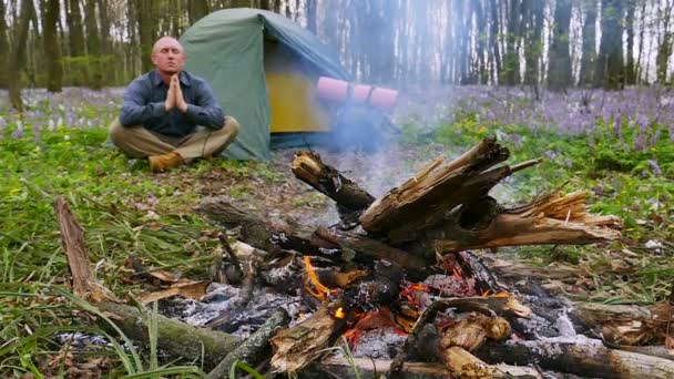 Zeitlupe bei 100 fps. Erwachsener Mann meditiert am Lagerfeuer und im Zelt — Stockvideo