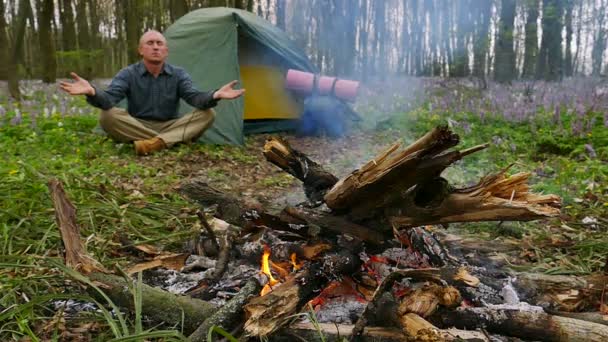 Mouvement lent à 100 FPS. Homme adulte près de feu de camp et tente médite — Video