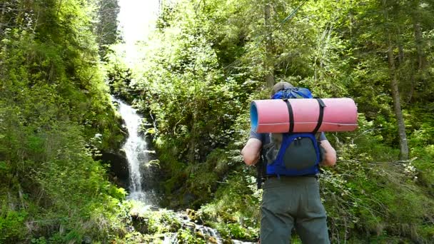 Movimento lento. Homem turista mochileiro perto de cachoeira — Vídeo de Stock