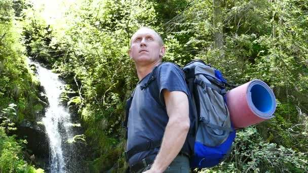 Slow motion. Man tourist stand backpacker near waterfall — Stock Video