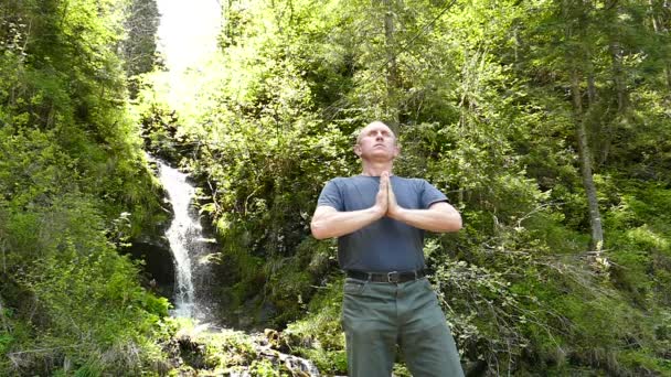 Movimento lento. O homem faz meditação perto da cachoeira. Mudança de foco — Vídeo de Stock