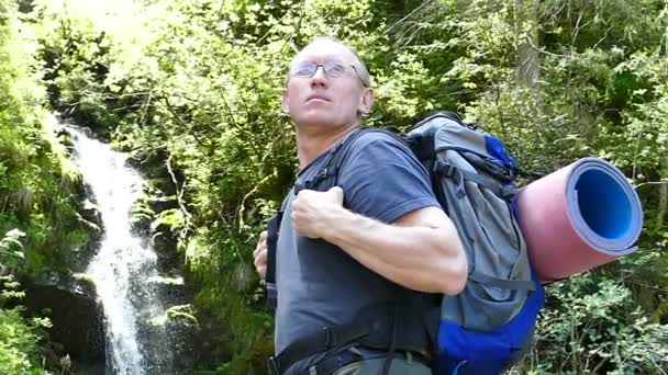 En cámara lenta. Hombre mochilero pie turístico cerca de la cascada. Cambio de enfoque — Vídeos de Stock