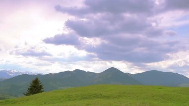  Dağ tepeleri, yalnız ağaç ve bulutlar gökyüzünde. Zaman atlamalı manzara