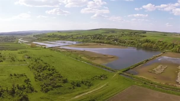 Antenne. Flug über grüne Wiese mit Seen in der Ferne — Stockvideo