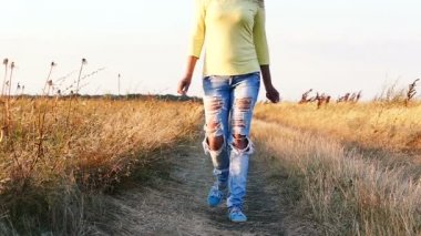  Ağır çekim. G.Pasquali yetişkin kadın moda kot pantolon toprak yolda gidiyor 
