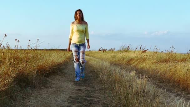 Slow motion. Serios kvinna i fashionabla jeans går på grusväg. Kamera flytta — Stockvideo