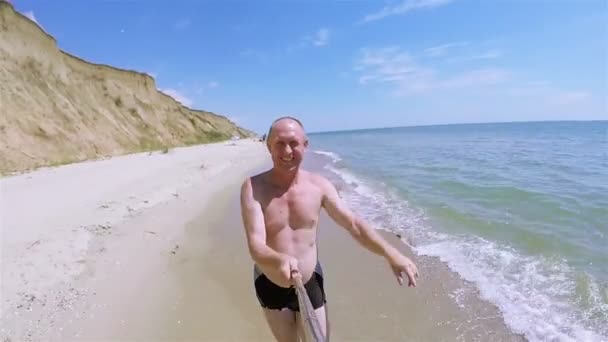 Дорослий щасливий чоловік робить селфі на березі моря і посміхається — стокове відео