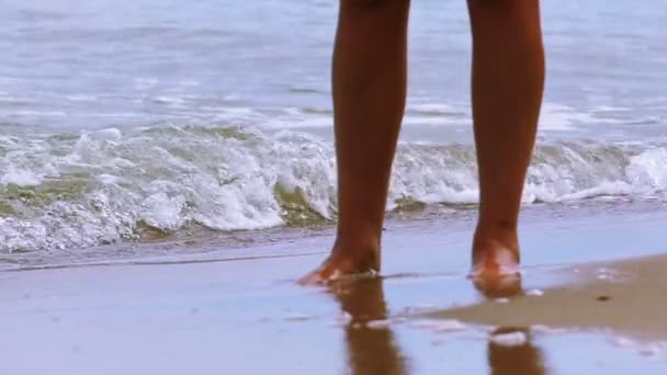 Медленное движение. Женские ноги стоят на берегу моря среди волн — стоковое видео
