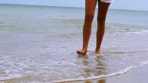 Movimento lento. pernas femininas ir na costa do mar entre as ondas — Vídeo de Stock