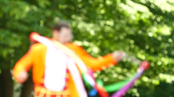 Al rallentatore. Giocoliere sorridente con nastri nel parco cittadino. Scena offuscata — Video Stock