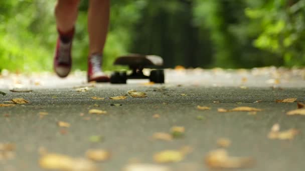 Dospívající dívka nohy s skateboard v zeleném parku přístupu. Zpomalený pohyb — Stock video