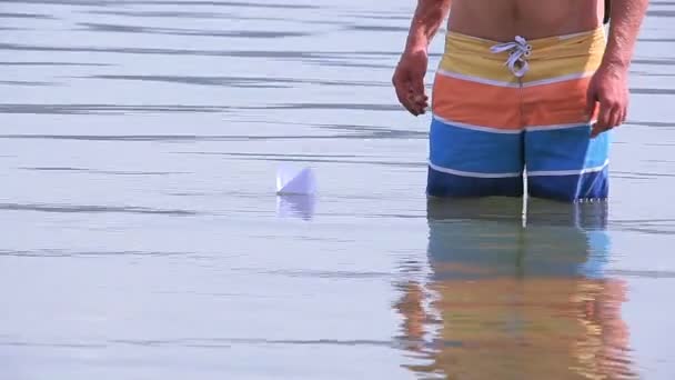 Kinderreiz. Mann startet Papierschiffe im Seewasser — Stockvideo