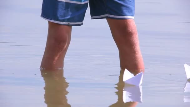 童年的吸引力。男生开始用纸船在湖里的水 — 图库视频影像