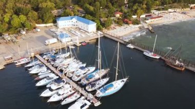 4K Havacılık. Güneşli bir günde tekneleri ve yatları olan bir liman. Kamera eğikliği