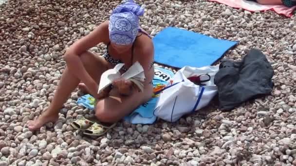 Das Mädchen liest das Buch am Strand — Stockvideo