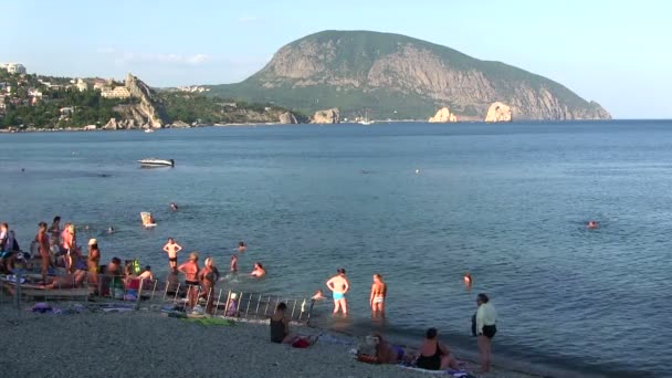 Beach on sea coast with silhouettes of people — Stock Video