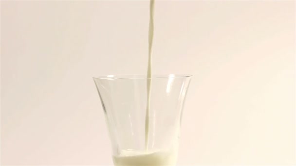 Milch fließt in einer transparenten Tasse — Stockvideo