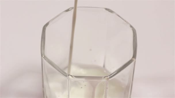 Milch fließt in transparentem Becher. Nahaufnahme — Stockvideo