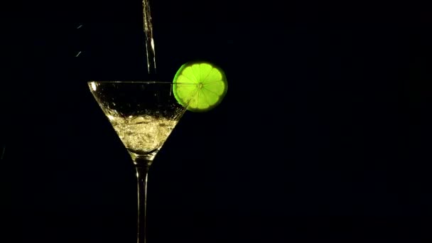 Cocktail with a slice a green lime on a dark background — Stock Video