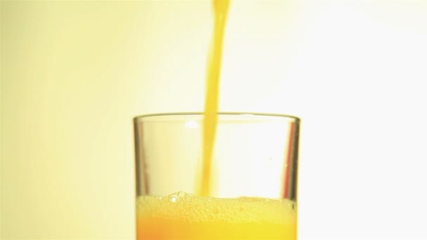 Jugo de naranja brillante que fluye en un vaso de cerca — Vídeos de Stock