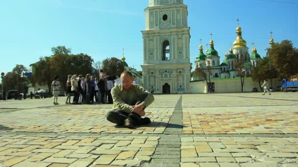 Smutný muž sedí na chodníku proti církvi. Časová prodleva — Stock video