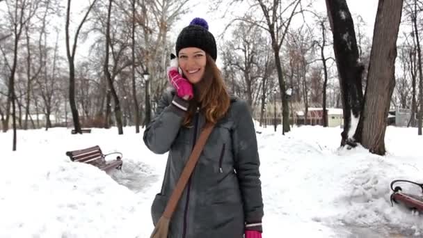 Jovem menina agradável fala por telefone celular no parque de inverno . — Vídeo de Stock