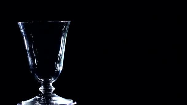 Белое стекло вращается на черном фоне — стоковое видео