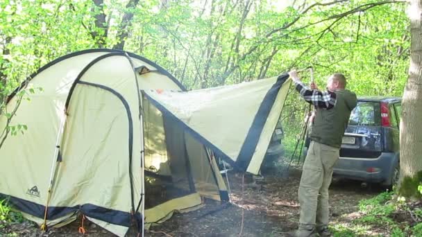 Two tourists with car, putting tent in  wood — Stock Video