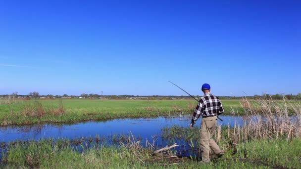 Чоловік ловить рибу на озері в яскравий день — стокове відео