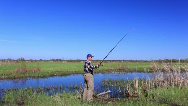 Homme pêcheur capture du poisson sur le lac dans la journée brillante — Video