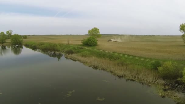 Paisaje con tractor de arado y río. Vista aérea de naturaleza — Vídeos de Stock