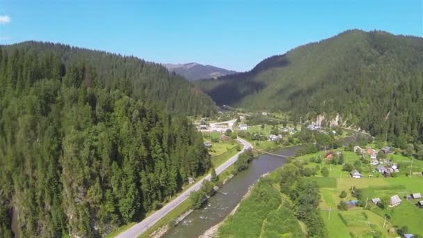 Let s poklesem řeku a vesnici v horách. Letecký snímek — Stock video