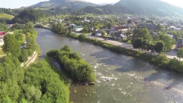 Dorf in Tal und Fluss. Luftaufnahme in kleinen Bergen — Stockvideo