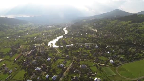 Dorf in einem kleinen Bergtal mit Sonnenstrahlen. Luftbild-Panorama — Stockvideo