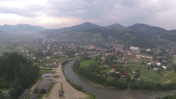 Dorp in vallei in bewolkte dag. Luchtfoto — Stockvideo