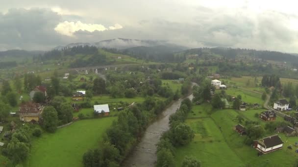 Αγροτικές ορεινές περιοχές με χωριό σε συννεφιασμένη μέρα. Εναέρια — Αρχείο Βίντεο