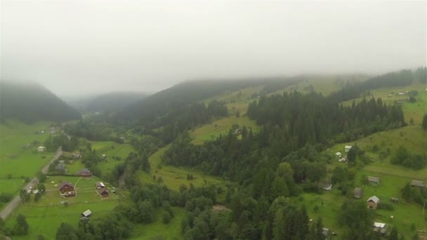 Laterale vlucht over mist, bergen en dorp. Luchtfoto — Stockvideo