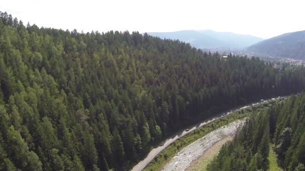 Langsamer Flug über das Flusstal mit Straße und Bergen. Antenne — Stockvideo