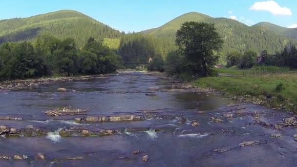 Über Gebirgsfluss und Dorf fliegen. — Stockvideo