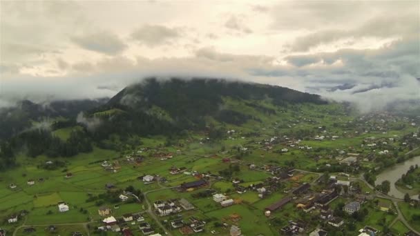 Montagne nuvolose con villaggio nella valle. Colpo aereo — Video Stock