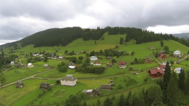 Зеленый холм с поселением в горах. Боковой полет с воздуха 40 секунд — стоковое видео