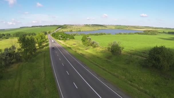 Autoroute avec voitures et beau lac dans les collines. Vol arrière aérien — Video