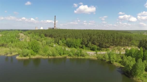 Vlucht over meer, hout met silhouet van fabriek pijp. Luchtfoto — Stockvideo