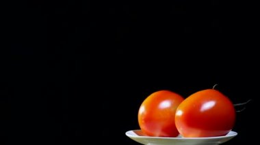 İki domates beyaz tabak, siyah arka plan üzerinde döner