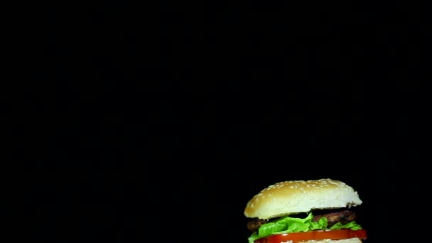 Hamburger con patata fritta a rotazione su fondo nero . — Video Stock