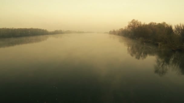 Río místico al amanecer con niebla en tonos anaranjados. Vista trasera aérea — Vídeo de stock